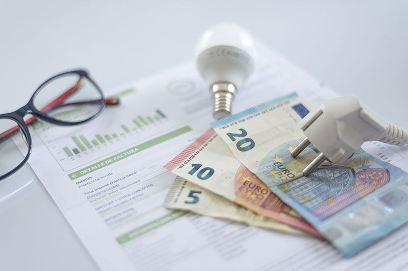 Imagen de un enchufe, una bombilla, dinero y debajo una factura de energía. Imagen que hace referencia a las reclamaciones.