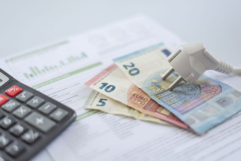 Imagen de un enchufe, una calculadora, dinero y debajo una factura de energía. Imagen que hace referencia a las reclamaciones.